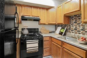 Baltimore apartment for rent - a kitchen with black appliances and wooden cabinets