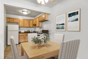 Oxon Hill apartment for rent - a dining room with a wooden table and chairs and a kitchen with a refrigerator