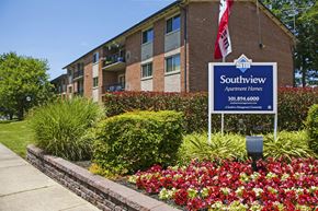 Oxon Hill apartment for rent - an apartment building with a sign in front of a flower garden