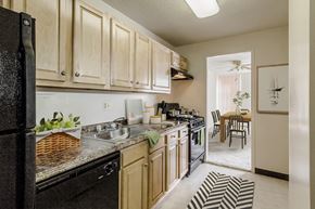 Silver Spring apartment for rent - a kitchen with white cabinets and black appliances and a dining room with a table