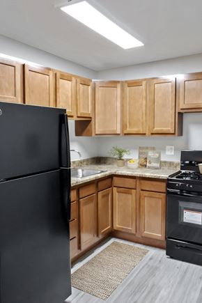 Riverdale apartment for rent - A black refrigerator stands in a kitchen with wooden cabinets.