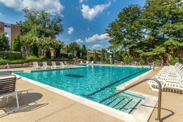 Windsor Mill apartment for rent - a swimming pool with chairs and trees and a building in the background