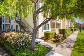 Gilroy apartment for rent - a sidewalk in front of a house with trees and flowers