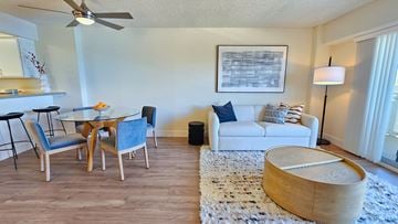 San Mateo apartment for rent - A living room with a white couch, a wooden coffee table, and a dining table with chairs.