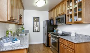 Cupertino apartment for rent - a kitchen with wood cabinets and granite counter tops and a black refrigerator