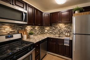 Reisterstown apartment for rent - A kitchen with dark brown cabinets and a black stove top oven.