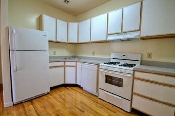 Orange apartment for rent - an empty kitchen with white appliances and white cabinets
