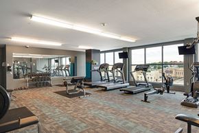 Omaha apartment for rent - a gym with exercise equipment and windows with a view of the city