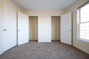 Orange apartment for rent - bedroom with two closets, off-white walls and carpeted floors