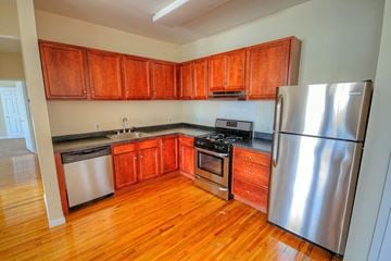 Orange apartment for rent - a kitchen with wooden cabinets and stainless steel appliances