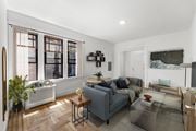 Jersey City apartment for rent - A living room with a grey couch, a coffee table, and a large window.