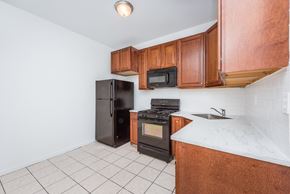 Jersey City apartment for rent - a kitchen with wooden cabinets and a black refrigerator