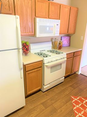 Lowell apartment for rent - A kitchen with wooden cabinets and a white stove top oven.