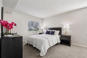 Southgate apartment for rent - A bedroom with a large bed and a nightstand with a lamp.
