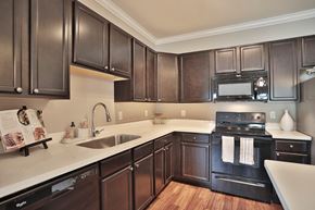 Jeffersontown townhouse for rent - A kitchen with dark wood cabinets and a white countertop.