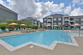 Jeffersontown townhouse for rent - A large swimming pool with a stone wall and a building in the background.