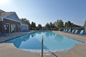 West Chester townhouse for rent - A large outdoor swimming pool with a building to the left and sun loungers on the right.