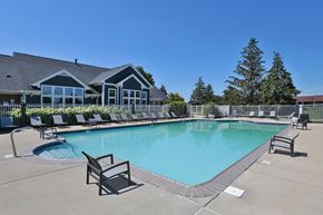 Fishers townhouse for rent - A large swimming pool with lounge chairs and a building in the background.