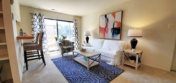 Glen Burnie apartment for rent - A living room with a white couch, a blue rug, and a painting on the wall.