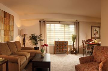 Essex apartment for rent - A living room with a brown sofa, a wooden cabinet, and a table with a vase of flowers.