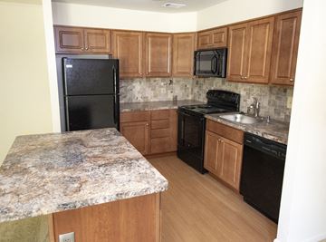 Catonsville apartment for rent - A kitchen with a granite counter top and black appliances.