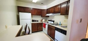 Catonsville apartment for rent - A kitchen with white appliances and wooden cabinets. at White Oaks Apartments, Catonsville, MD