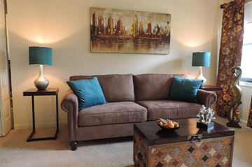 Parkville apartment for rent - A brown couch with blue pillows sits in a living room with a painting on the wall.
