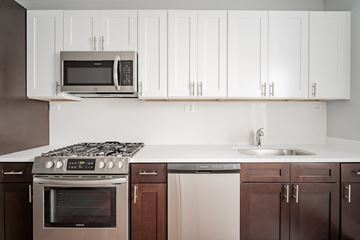 Chicago apartment for rent - a kitchen with white cabinets and a stove and a microwave