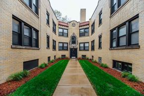 Chicago apartment for rent - an exterior view of a brick building with a sidewalk and grass