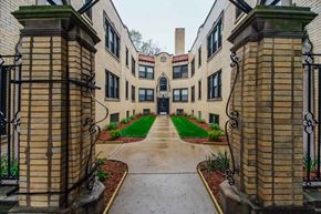 Chicago apartment for rent - the entrance to a building with a green lawn and walkway