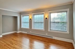 Oak Park apartment for rent - Three windows with blinds in a room with wooden floors.
