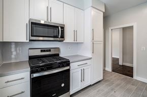 Montclair apartment for rent - a kitchen with white cabinets and a stove and a microwave