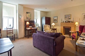 Boston apartment for rent - A living room with a purple couch and a fireplace.