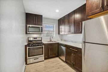 Orange apartment for rent - an empty kitchen with wooden cabinets and stainless steel appliances
