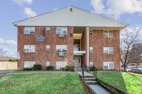 Orange apartment for rent - a red brick apartment building with a lawn and stairs