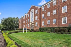 Upper Montclair apartment for rent - a large brick building with a green lawn in front of it