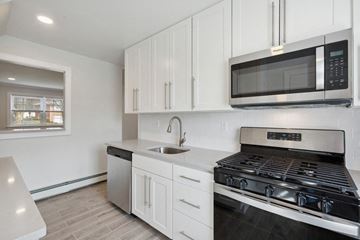 Edison apartment for rent - a kitchen with white cabinets and a stove and a microwave
