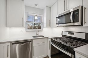 Clark apartment for rent - a kitchen with white cabinets and stainless steel appliances and a microwave