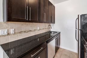 Bloomfield apartment for rent - a kitchen with dark cabinets and a sink and a refrigerator