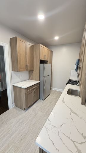 Jersey City apartment for rent - A kitchen with a marble countertop and wooden cabinets.