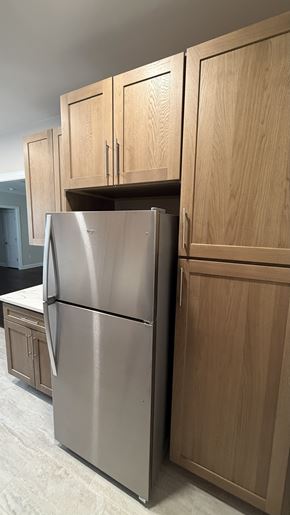 Jersey City apartment for rent - A stainless steel refrigerator is in a kitchen with wooden cabinets.