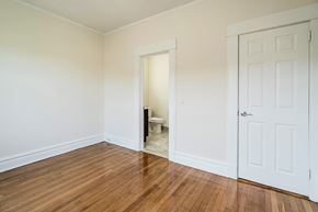 Bloomfield apartment for rent - a bedroom with white walls and wood flooring and a door to a bathroom