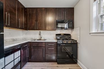 Woodbridge apartment for rent - A kitchen with dark wood cabinets and black appliances.