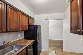 Colonia apartment for rent - A kitchen with a black fridge and wooden cabinets.