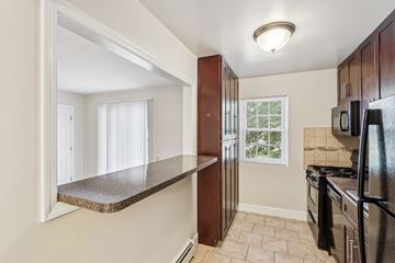 Colonia apartment for rent - A kitchen with a black refrigerator and a window with white curtains.