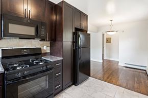 Woodbridge apartment for rent - a kitchen with black appliances and dark wood cabinets