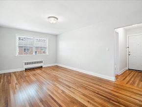 Orange apartment for rent - A room with wooden flooring and a window showing a building outside.