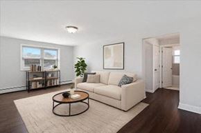 Bloomfield apartment for rent - A living room with a white couch, a coffee table, and a plant.