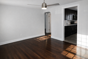 Long Branch apartment for rent - A room with a ceiling fan and a kitchen in the background.