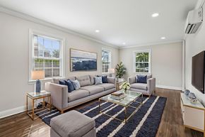Summit apartment for rent - A living room with a grey sofa, a glass coffee table, and a television.